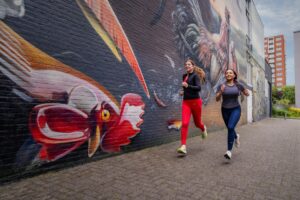 foto van vrouwen die hardlopen langs muurschilderingen in het project van het Mauritshuis